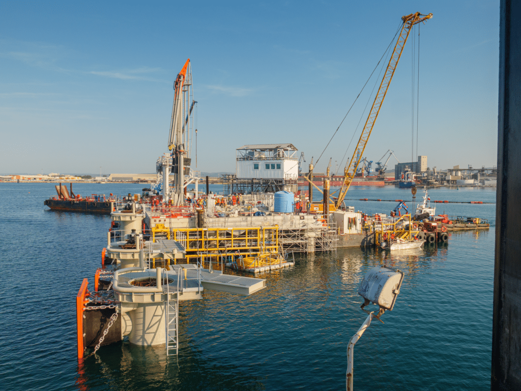 Vue d’un chantier maritime montrant une plateforme de construction flottante avec des grues, des équipements de levage et des ouvriers, au port de Sète-Frontignan.
